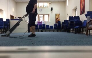 This image shows a man using a vacuum to clean a carpet.