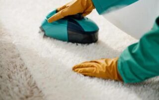 A vacuum is being used to clean a white and brown carpet.
